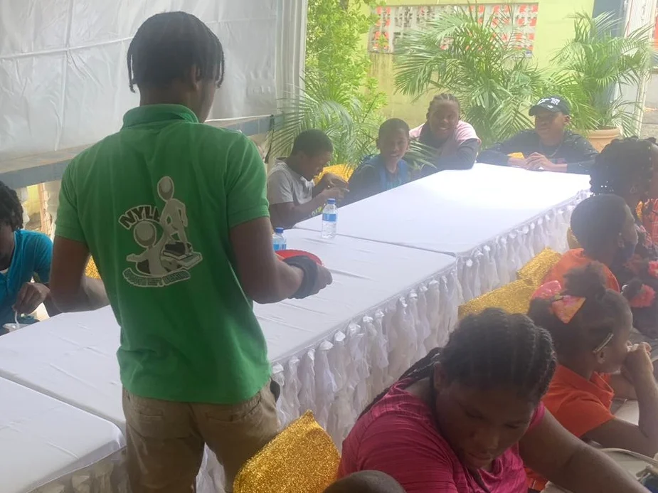NYLB youth facilitator presenting to children seated around a table.
