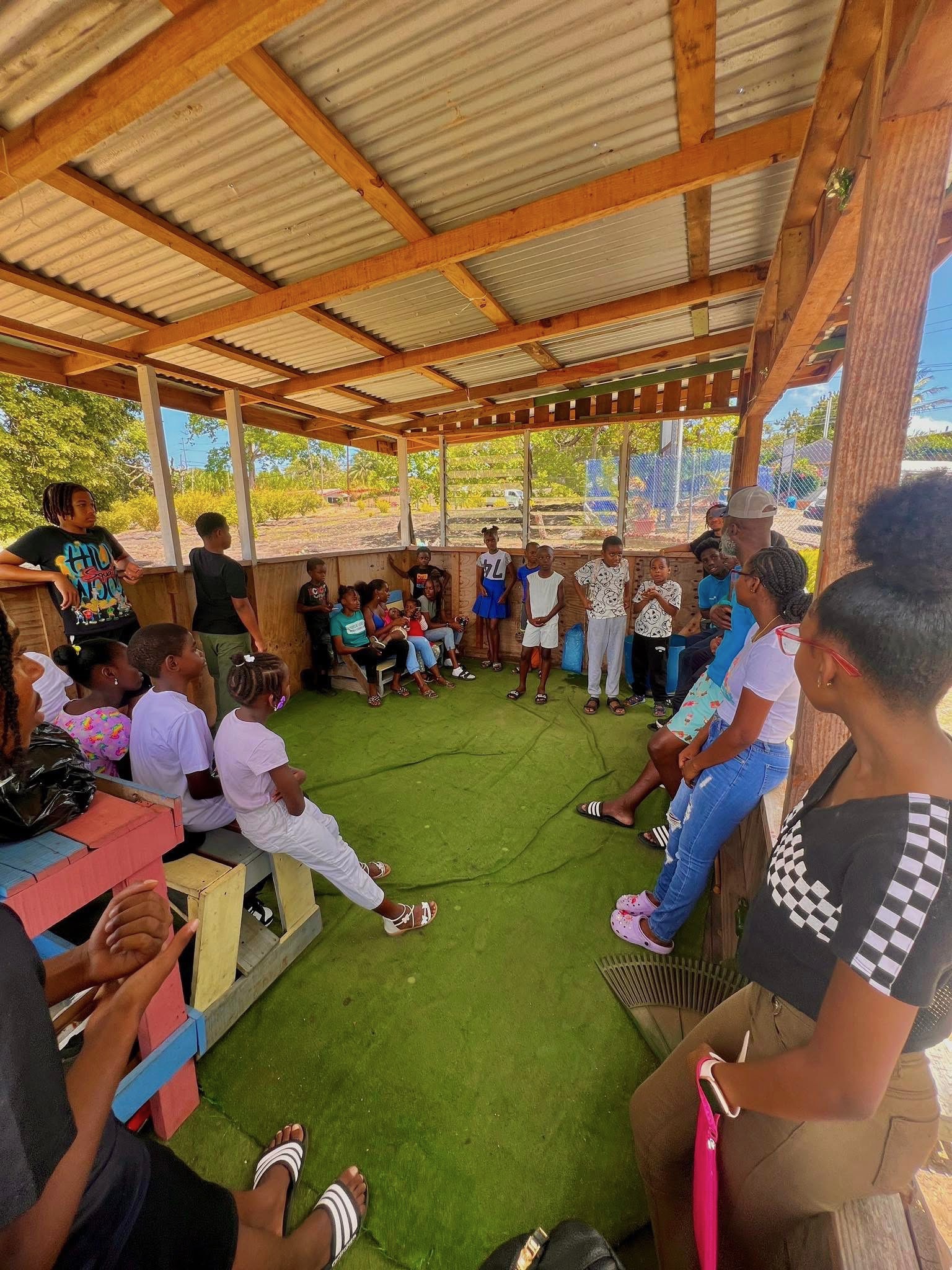 NYLB youth and facilitators seated in a circle under an open pavilion.